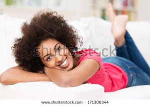 stock-photo-beautiful-laid-back-african-american-woman-relaxing-barefoot-on-her-stomach-on-the-sofa-at-home-171306344